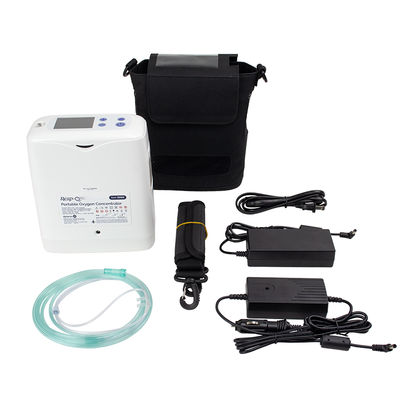 A portable oxygen concentrator kit laid out on a white background, including a white concentrator unit, black carrying case, tubing, power adapters, and a black strap with a yellow band.