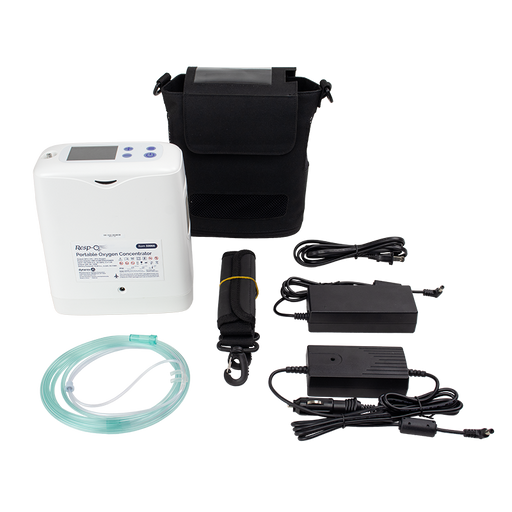 A portable oxygen concentrator kit laid out on a white background, including a white concentrator unit, black carrying case, tubing, power adapters, and a black strap with a yellow band.
