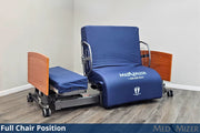 Blue Med Mizer chair in full chair position on a wooden floor with a white wall background.