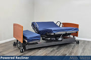 Powered recliner bed with wooden sides and blue mattress in a room setting.