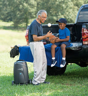 Man and child playing with a ball on a truck bed in a park