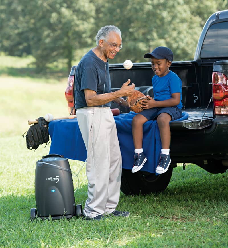 Man and child playing with a ball on a truck bed in a park