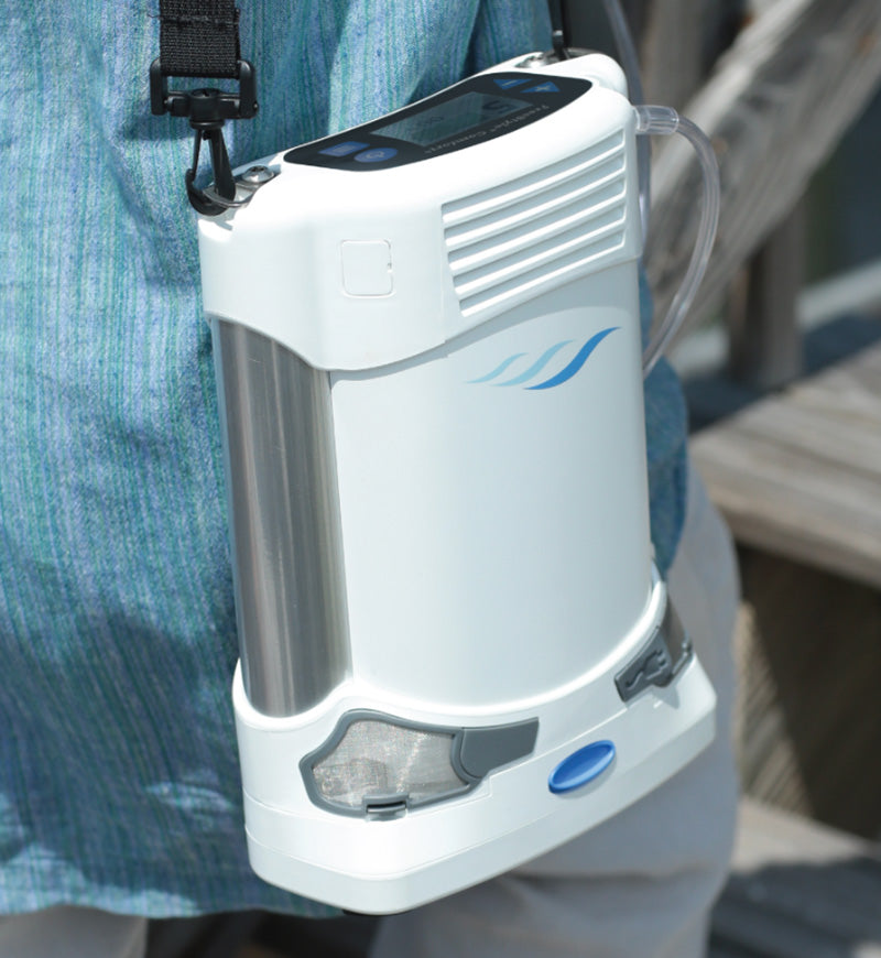 Portable concentrator device attached to a person's waist with a blurred background