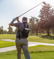 Man playing golf on a sunny day with trees in the background