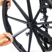 Close-up of a person adjusting a black bicycle wheel with a tool on a white background