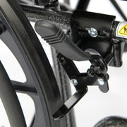 Close-up of a wheelchair brake lever and caliper on a blurred background