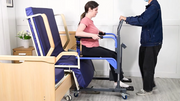Person using a transfer board to help another person into a chair.