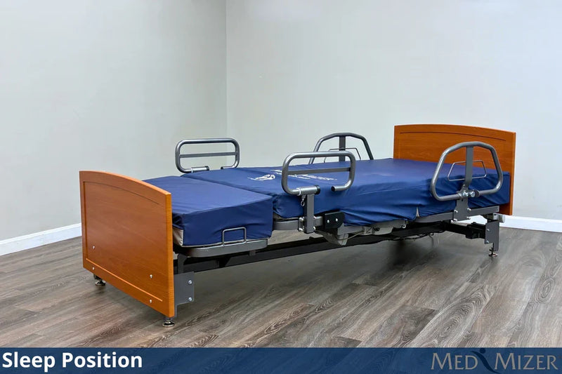 Hospital bed in a sleep position with wooden head and footboards on a wooden floor.