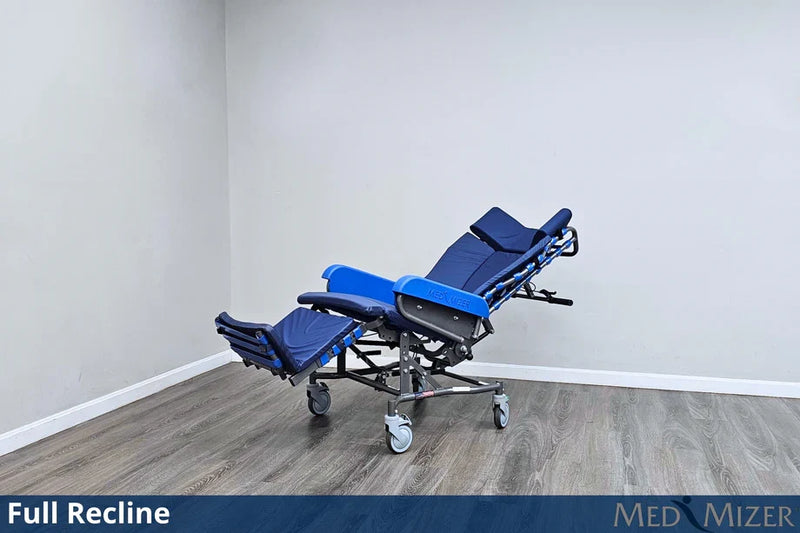 Blue reclining medical chair on a wooden floor with a white wall background