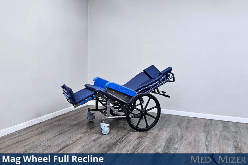 Blue reclining wheelchair with mag wheels in a room with gray walls and wooden floor.