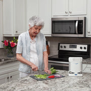Woman preparing food in a kitchen with a portable air concentrator on the counter.