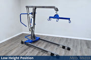 Medical lift device in a room with wooden flooring and white walls.