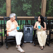 Two women sitting on a wooden deck with a portable power station between them.