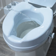 Close-up of a bidet attachment on a toilet with water flowing.