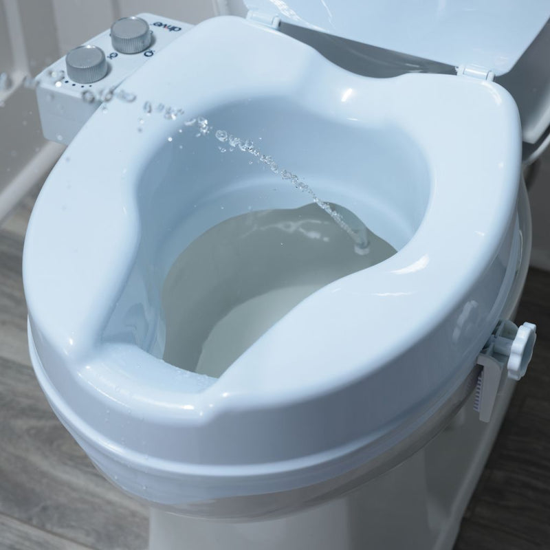 Close-up of a bidet attachment on a toilet with water flowing.