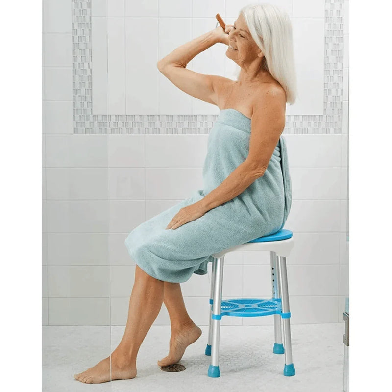 Woman sitting on a step stool in a bathroom wearing a light blue towel.