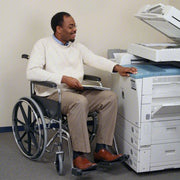 Man in a wheelchair using a printer in an office setting