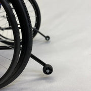 Close-up of a wheelchair wheel on a light gray floor
