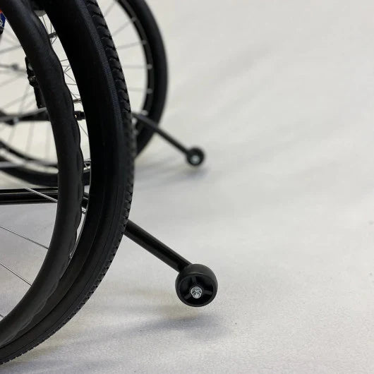 Close-up of a wheelchair wheel on a light gray floor
