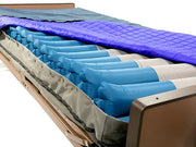 An air mattress with multiple blue inflatable air chambers and a gray fabric liner, shown with a purple quilted mattress cover on a white background.