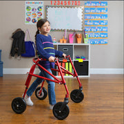 Child using a red walker in a classroom setting