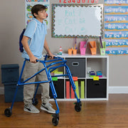 Young boy using a walker in a classroom setting with educational posters and supplies.