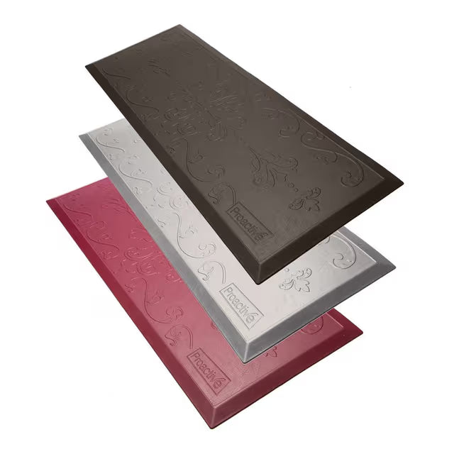 Three rectangular textured floor mats in dark brown, silver, and red, stacked diagonally on a white background. Each mat features an embossed floral scroll pattern and a small embossed brand logo that reads 'Prestige'.