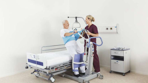 Person using a hospital lift in a medical setting with a nurse assisting.
