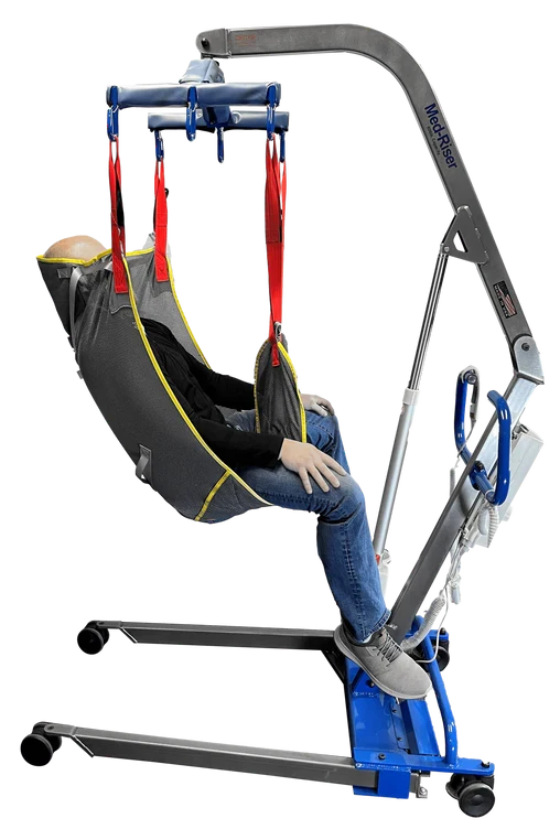 A motorized patient lift chair with a gray and black sling seat, red straps, and a blue base, shown with a mannequin or person seated inside on a white background.