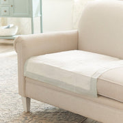 Beige sofa with a transparent pet barrier on a wooden floor in a living room.
