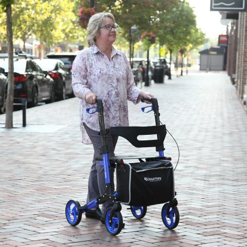 Woman using a rollator on a sidewalk with trees and parked cars in the background